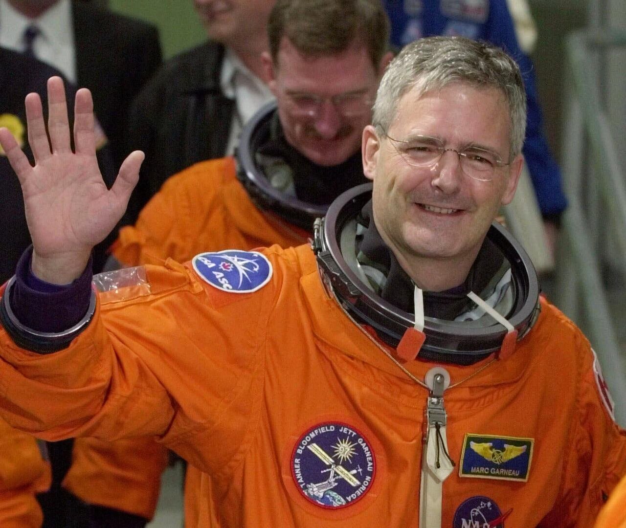 default-325 Marc Garneau, suited up for a spaceflight, waving to reporters in November 2000.